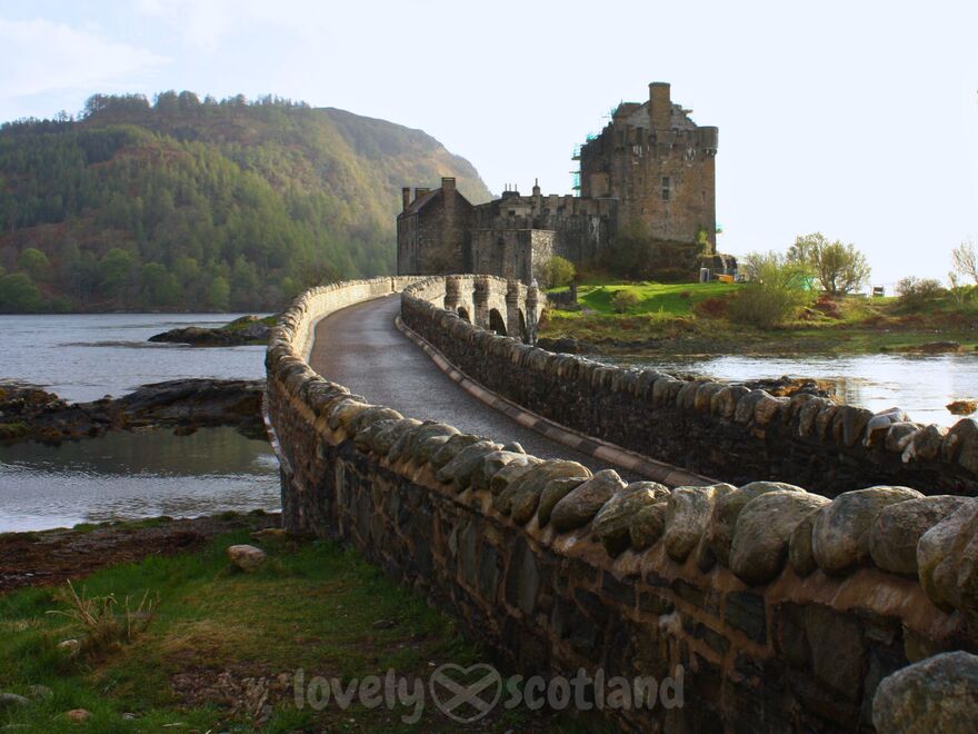 Eilean Donan Castle vu depuis le pont de pierre avec lochs et collines au fond