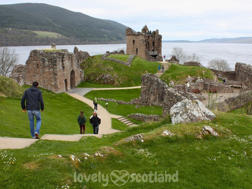 Ruinas del castillo de Urquhart sobre Loch Ness con visitantes recorriendo el recinto