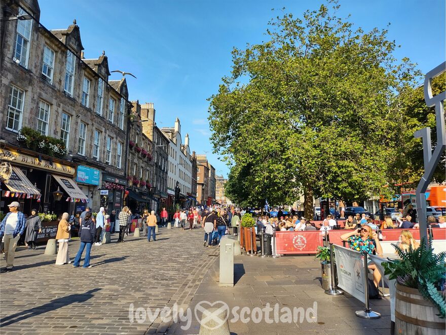 Ambiance ensoleillée au Grassmarket à Édimbourg, avec des terrasses animées