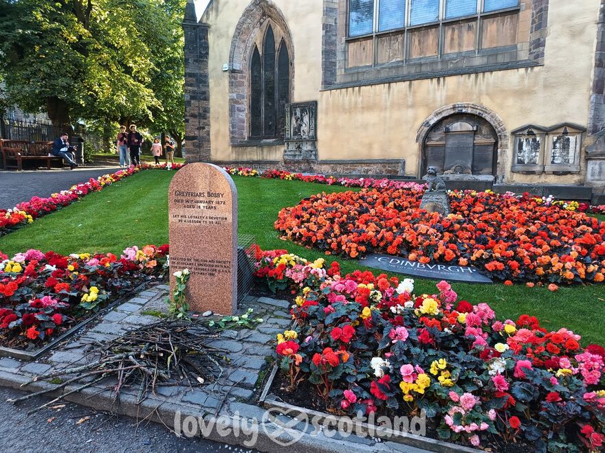 Tombe de Greyfriars Bobby avec fleurs et bâtons au Cimetière de Greyfriars