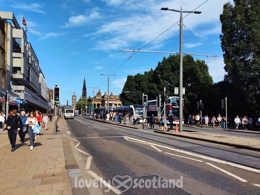 Princes Street animée à Édimbourg avec boutiques, bus et tramway