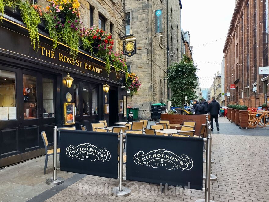 Exterior de un pub en Rose Street de Edimburgo con flores y parte de la calle