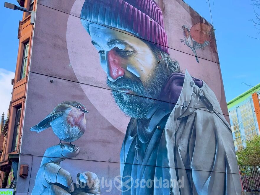 Gran mural de San Mungo en Glasgow con un petirrojo posado en su mano