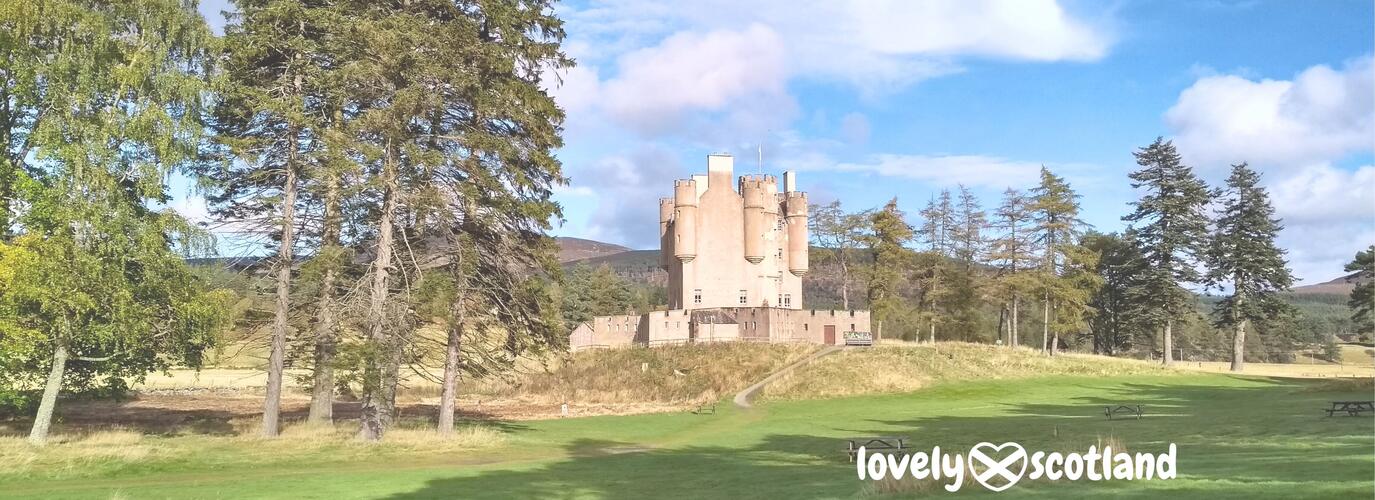 Braemar Castle exterior framed by pine trees and open lawns