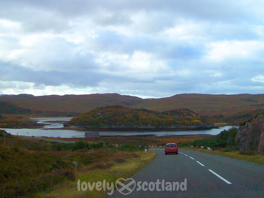 Route panoramique dans les Highlands avec lac montagnes et voiture rouge devant