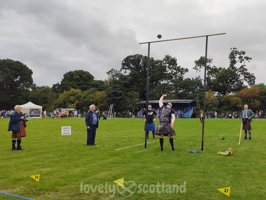 Athlete competing in a Highland Games weight throw as judges watch nearby