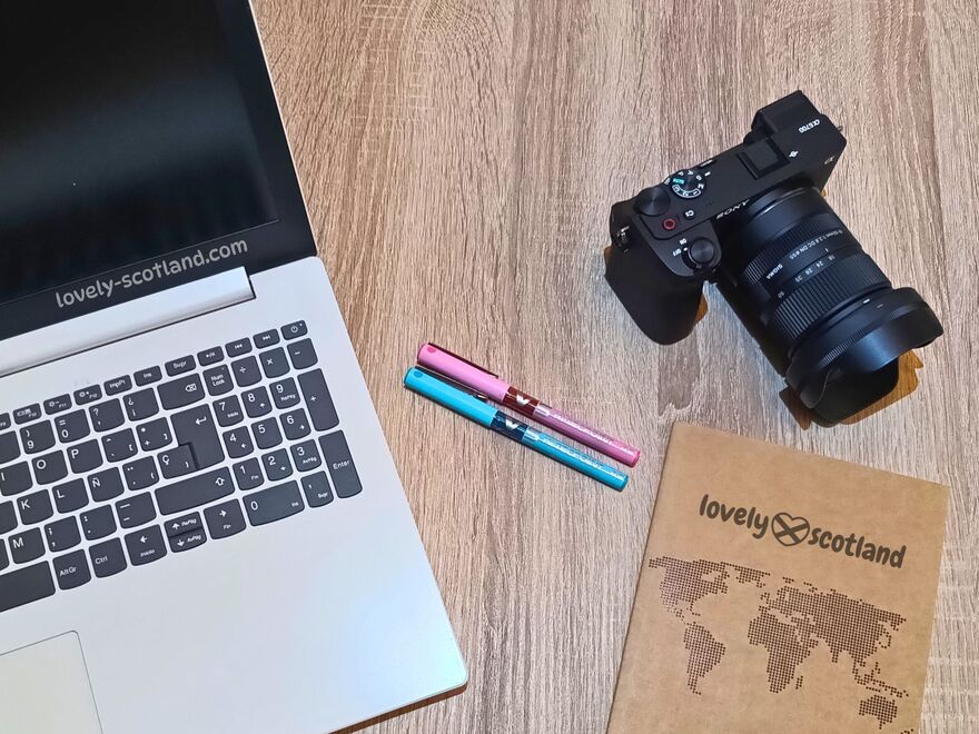Lovely Scotland travel blog workspace with laptop camera notebook and pens