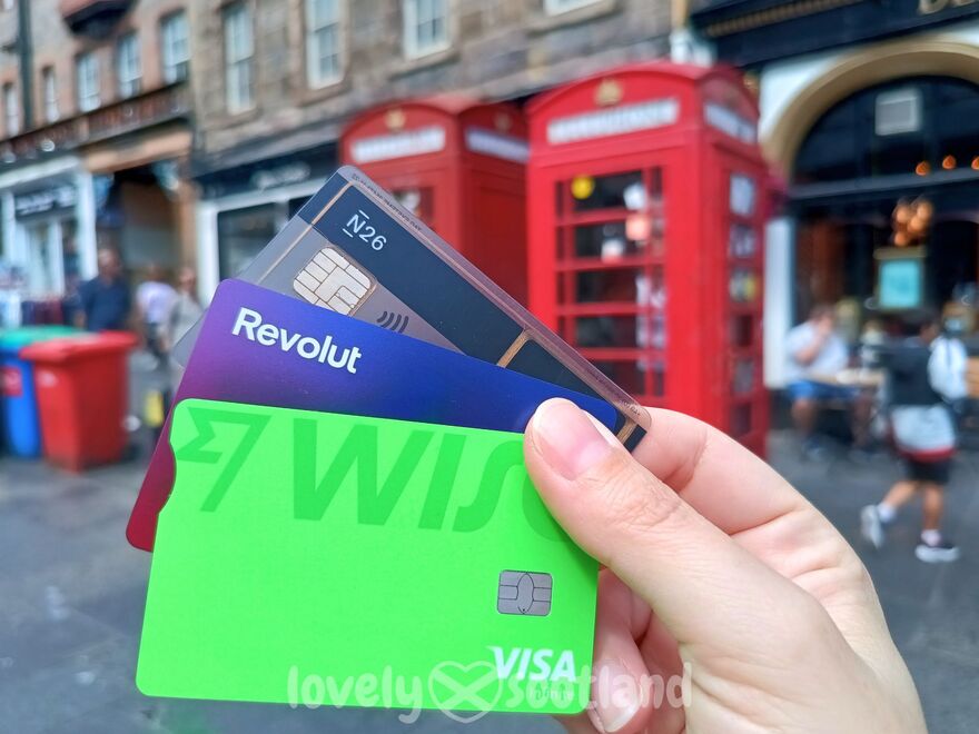 Cartes de paiement tenues en main avec cabines téléphoniques rouges en fond