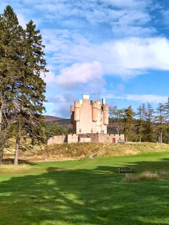 Braemar Castle exterior framed by pine trees and open lawns