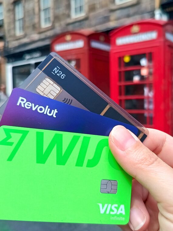 Travel payment cards held in hand with red telephone booths behind