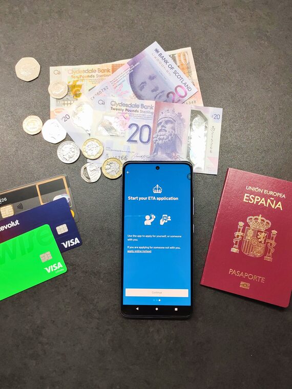 UK ETA application on phone with passport travel cards and pounds